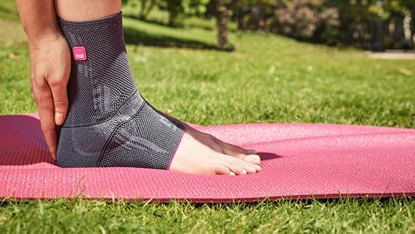 image shot of a pink and grey levamed  ankle brace on a pink yoga matt
