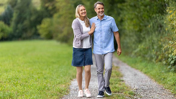 woman wearing compression tights walking in the arms of her husband on a path next to a forest