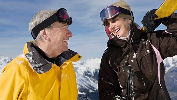 Two elderly people enjoying winter sports in the snowy alps, staying fit through the winter.