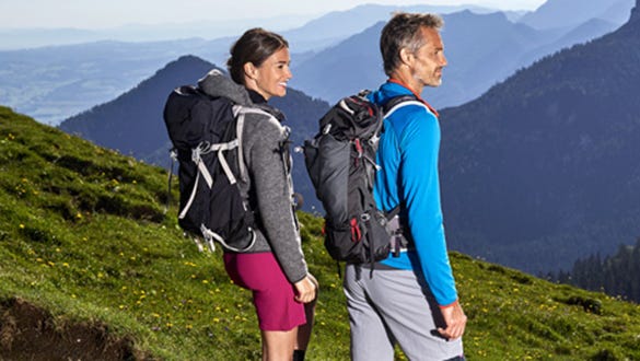couple hiking in the sunny green mountains and enjoying their scenic view