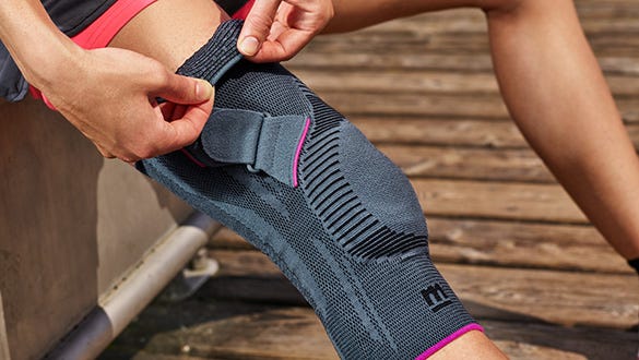 close up product shot of the orthopaedic  pink and grey Genumedi PT knee support