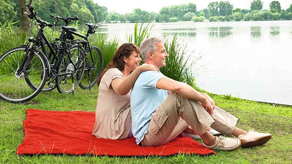 couple suffering from lipoedema  having a picnic on the lakeside after their biketour