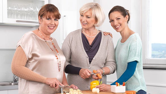 Three lipoedema and lymphoedema patients standing in a kitchen and chopping vegetables together