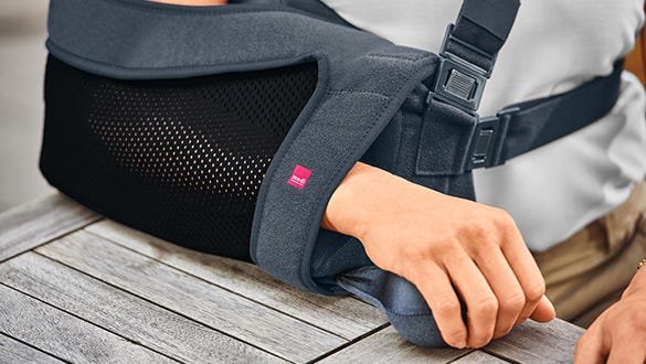 Image shot of a grey and pink medi shoulder support lying down on a table 