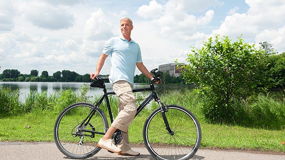 A senior showcasing his bike in front of a lake proving that even at 60 plus sport is possible