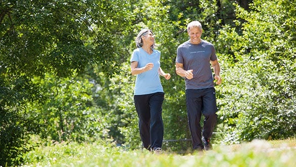 "happy elderly couple walking through  a green forest combining sport and leisure
