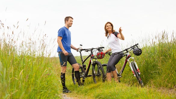 active couple on a biketour through green fields having an active holiday