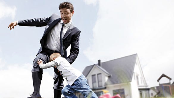 Father in a suit playing footbal with his son while wearing compression stockings