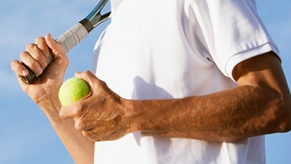 man wearing a white t-shirt and carrying his tennis gear with him