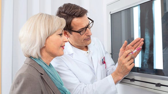 "elderly woman and her doctor analysing two radiographs of her spine and  buttocks