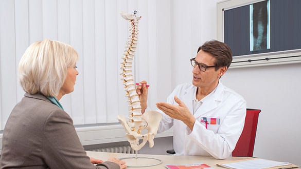 "Woman sitting in  her doctors office getting her spine structure explained
