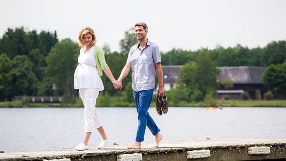 Pregnant couple holding hands while promenading, showcasing their medi active  compression socks