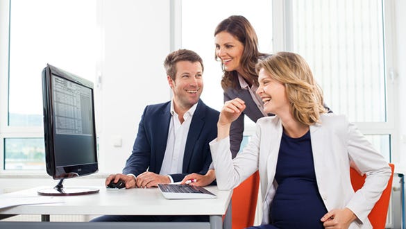 A pregnant woman laughing with her colleagues in the office,  showing work and pregnancy can align